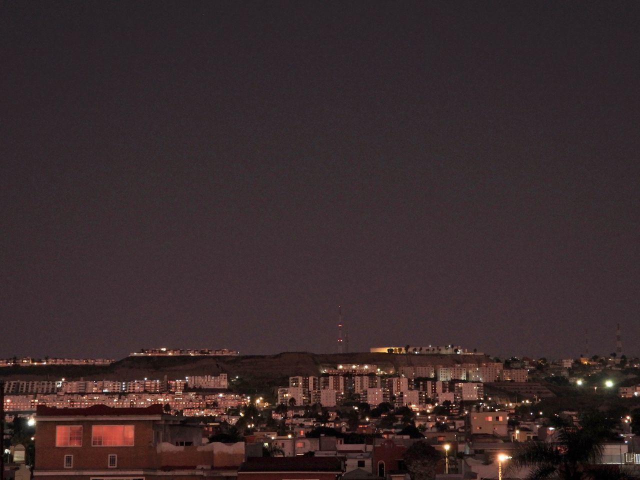 HIGH ANGLE VIEW OF ILLUMINATED BUILDINGS IN TOWN AGAINST SKY