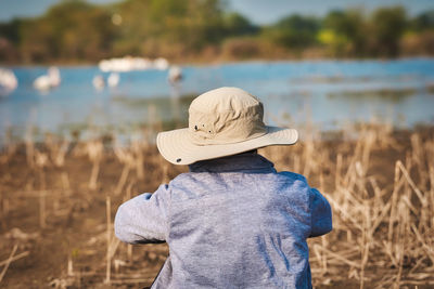 Rear view of man standing by lake