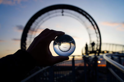 Close-up of hand holding glass against sky during sunset