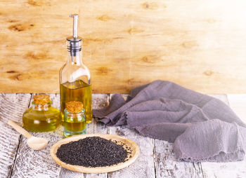 Oil and sesame seeds on wooden surface