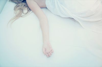 Low section of woman relaxing on bed