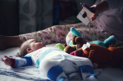 Low section of mother playing with baby while sitting on bed at home