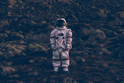 Astronaut standing on land against mountain