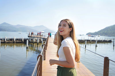 Portrait of young woman standing against lake