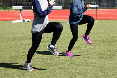 Two high school girls do a-skips during track and field practice