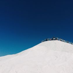 Scenic view of snow covered mountains against clear blue sky