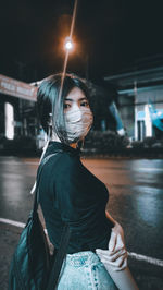 Portrait of woman standing on street at night