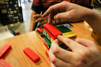 Cropped image of people playing jenga on table