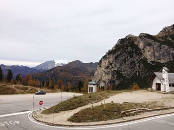 Street by mountains against cloudy sky