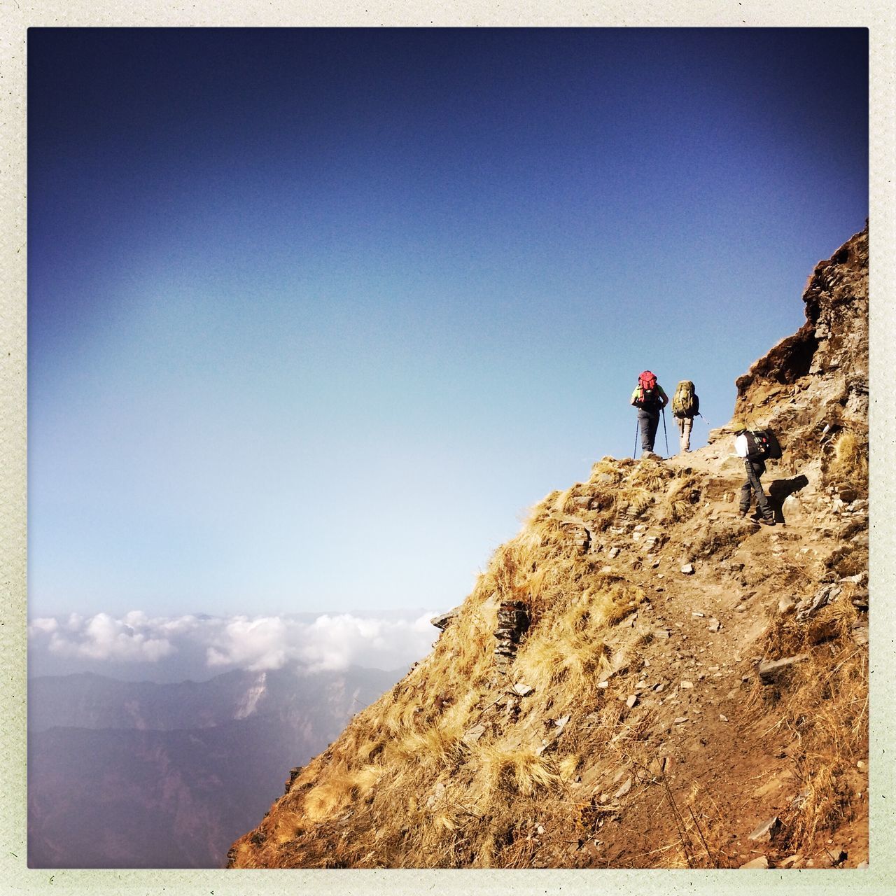 PEOPLE WALKING ON MOUNTAIN AGAINST SKY