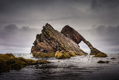 Rock formation in sea against sky