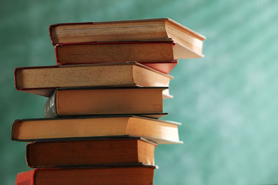 Close-up of stack of books on table against wall