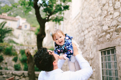 Portrait of smiling young woman standing against building