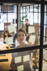 Businesswoman sticking adhesive notes during meeting in board room