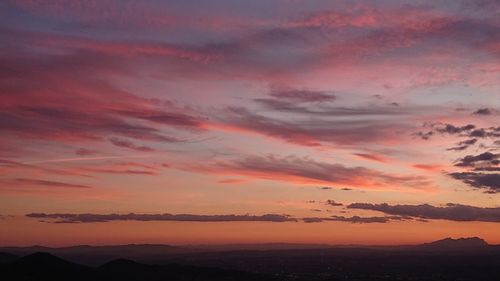 Scenic view of dramatic sky over silhouette landscape