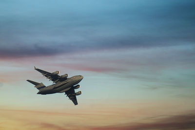 Low angle view of airplane against sky at sunset