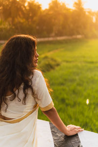 Rear view of woman using laptop on field