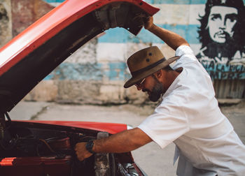 Side view of man standing against cars