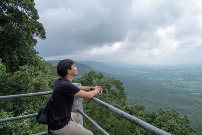 Side view of man looking at landscape against sky