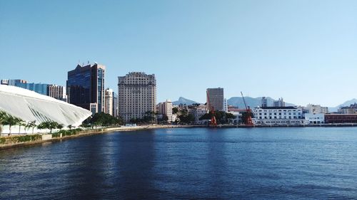 View of buildings by river against blue sky