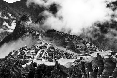 Ruined structures on landscape against clouds