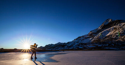 Man standing on mountain against clear blue sky