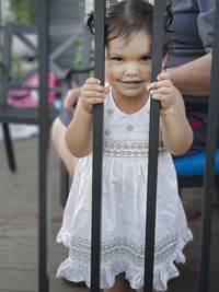 Portrait of cute girl standing by railing outdoors