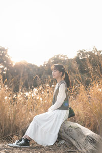 Woman sitting on field against clear sky