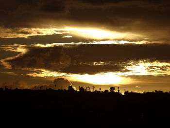 Silhouette landscape against dramatic sky during sunset