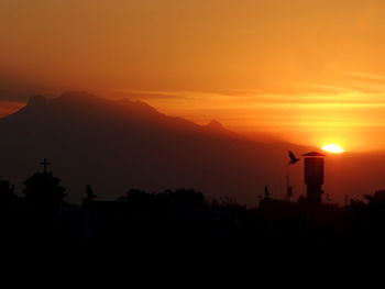 Scenic view of silhouette mountains against orange sky