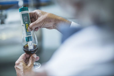 Distiller holding thermometer into shot glass