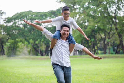 Full length of a happy young man with arms raised on grass