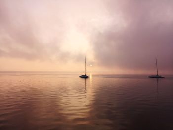 Sailboat in sea against sky during sunset