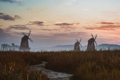 Windmill on field against sky during sunset