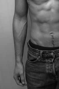 Midsection of shirtless man making face against black background