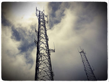 Low angle view of power lines against cloudy sky