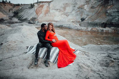 Rear view of couple sitting on rock