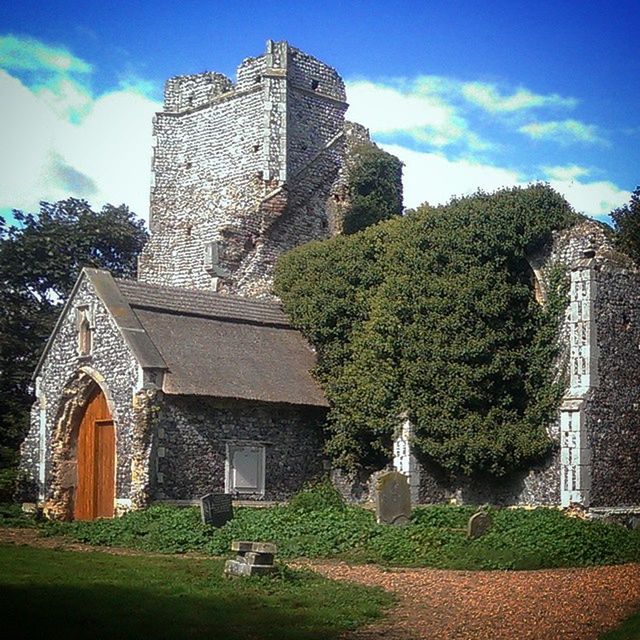 architecture, building exterior, built structure, sky, history, tree, church, religion, grass, place of worship, old, spirituality, cloud - sky, stone wall, low angle view, sunlight, the past, day, green color