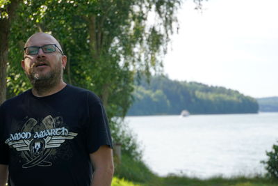 Portrait of mature man standing against lake