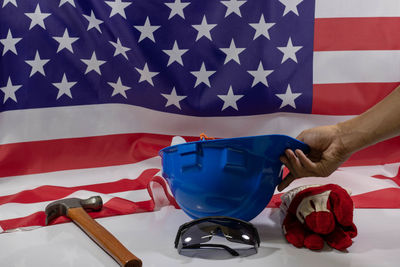 Close-up of hand holding flag against blue wall