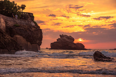 Rock formation on sea against sky during sunset