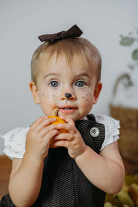Portrait of cute baby girl eating pumpkin at home