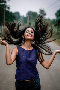 Young woman smiling while standing in the background