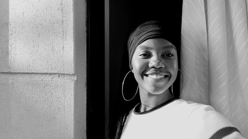 Close-up of smiling young woman against window