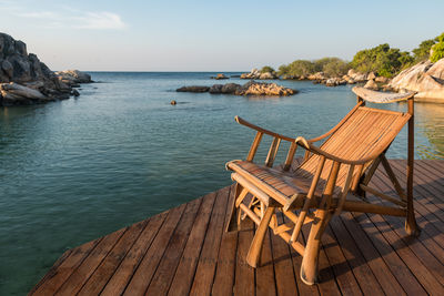 Wood armchair at resort patio by sea with stone arch in morning, ko man klang, rayong, thailand. 