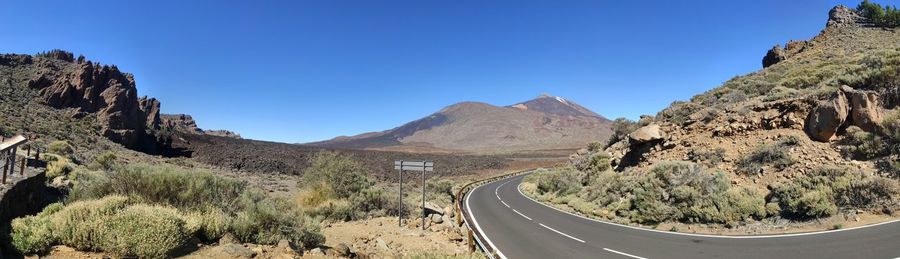 Panoramic view of road amidst mountains against clear blue sky