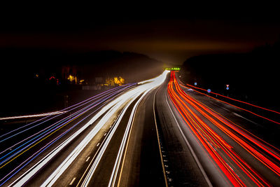 Light trails on road against sky at night