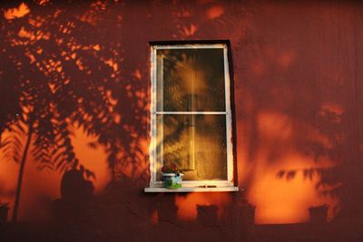 Illuminated lamp on table against wall at home