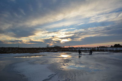 Scenic view of frozen lake against cloudy sky at sunset