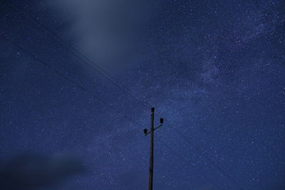 Low angle view of electricity pylon against star field at night